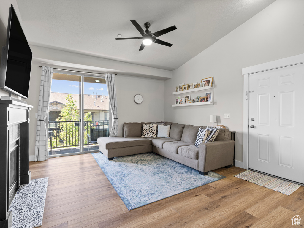 Living area with vaulted ceiling, ceiling fan, a fireplace with flush hearth, and wood finished floors