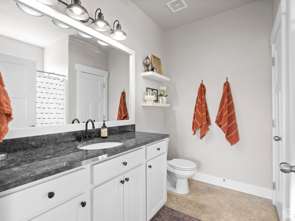 Full bath with vanity, toilet, baseboards, and tile patterned floors