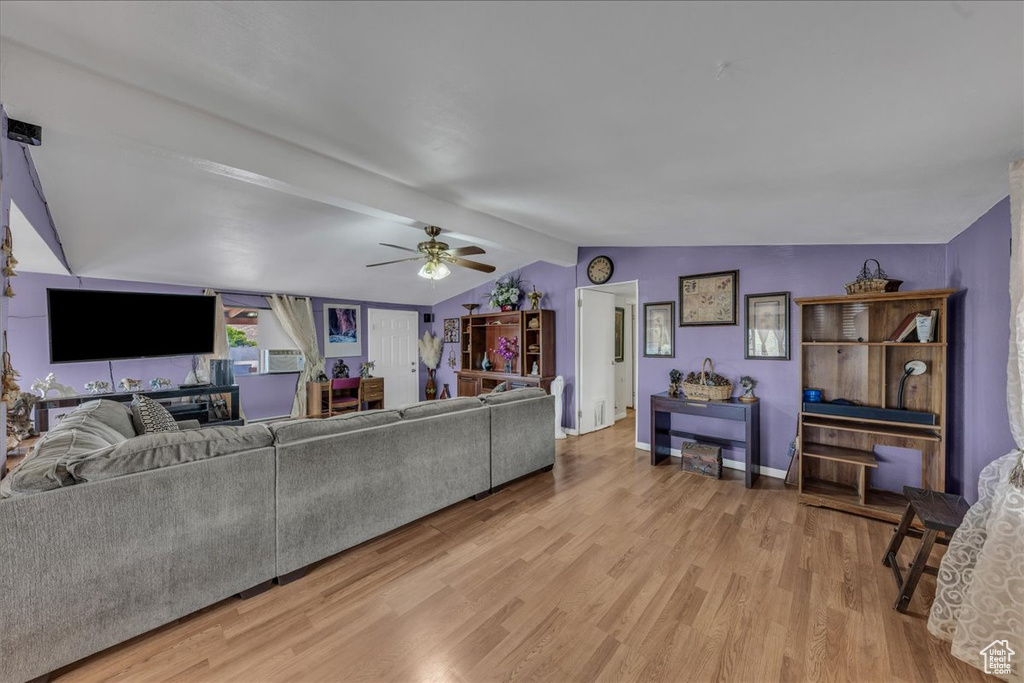 Living room with a ceiling fan, light wood-style flooring, and baseboards