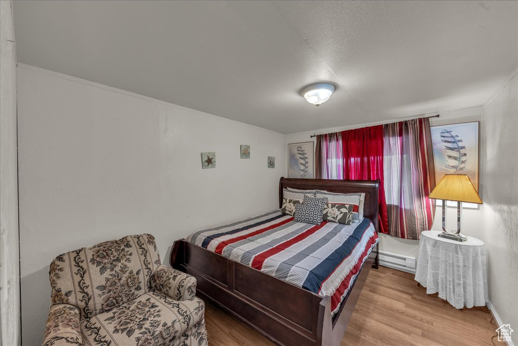 Bedroom with wood finished floors and baseboard heating