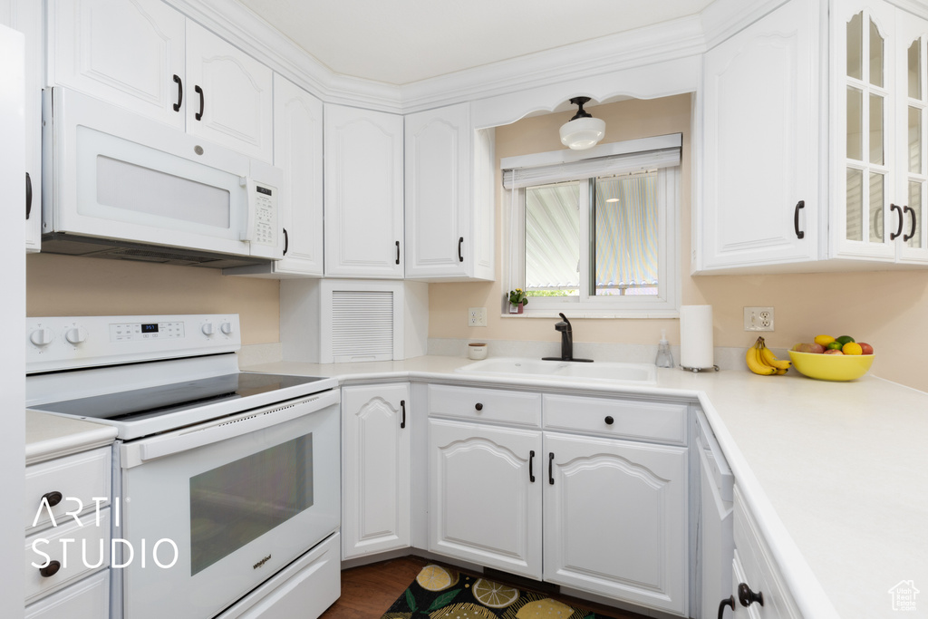 Kitchen featuring white appliances, a sink, white cabinets, glass insert cabinets, and light countertops