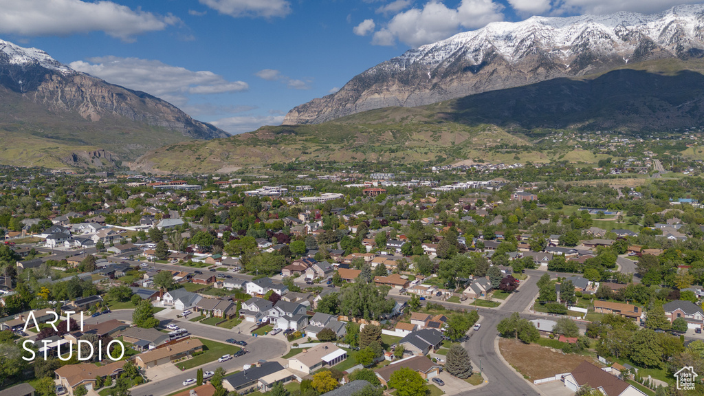 Aerial view of property and surrounding area featuring a mountainous background and nearby suburban area