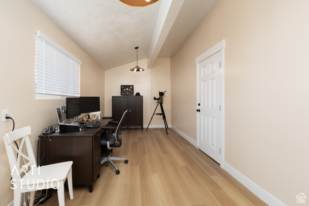 Office space with light wood-type flooring, vaulted ceiling, and baseboards