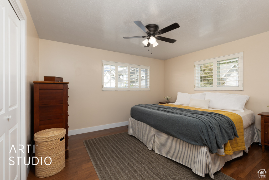 Bedroom with dark wood finished floors, baseboards, and a ceiling fan