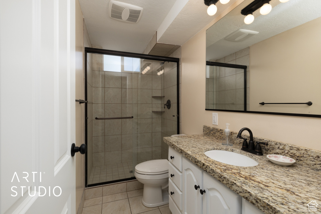 Bathroom with a stall shower, tile patterned flooring, vanity, and toilet