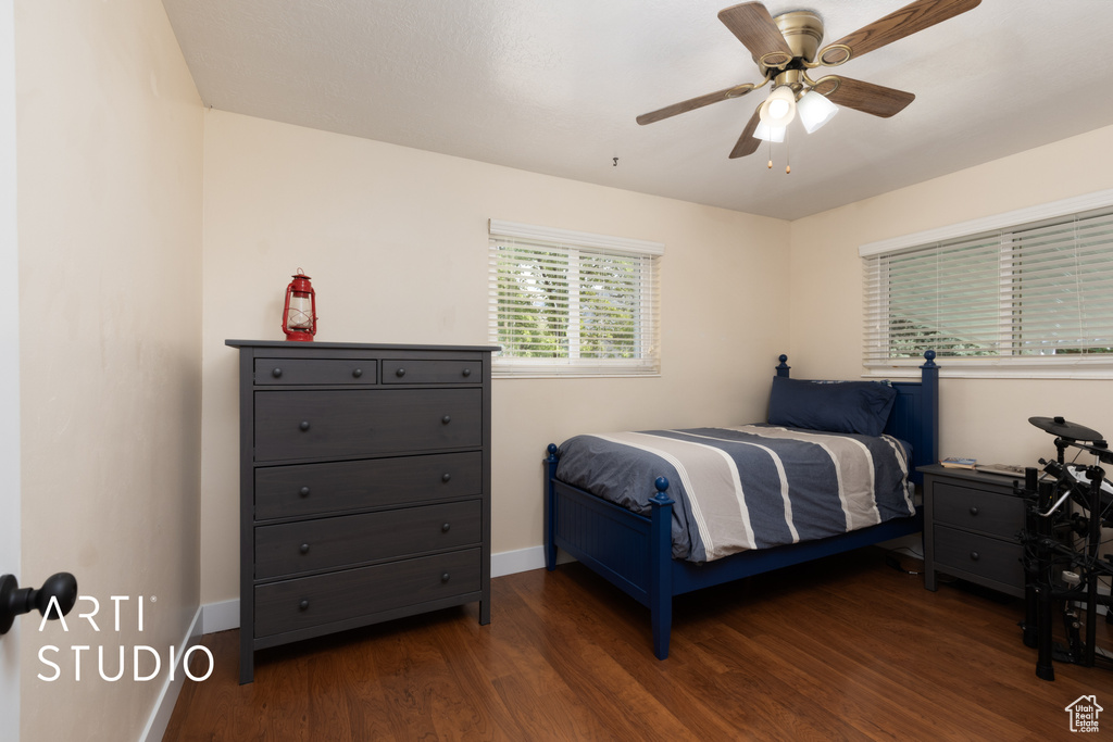Bedroom featuring dark wood-style flooring, baseboards, and a ceiling fan