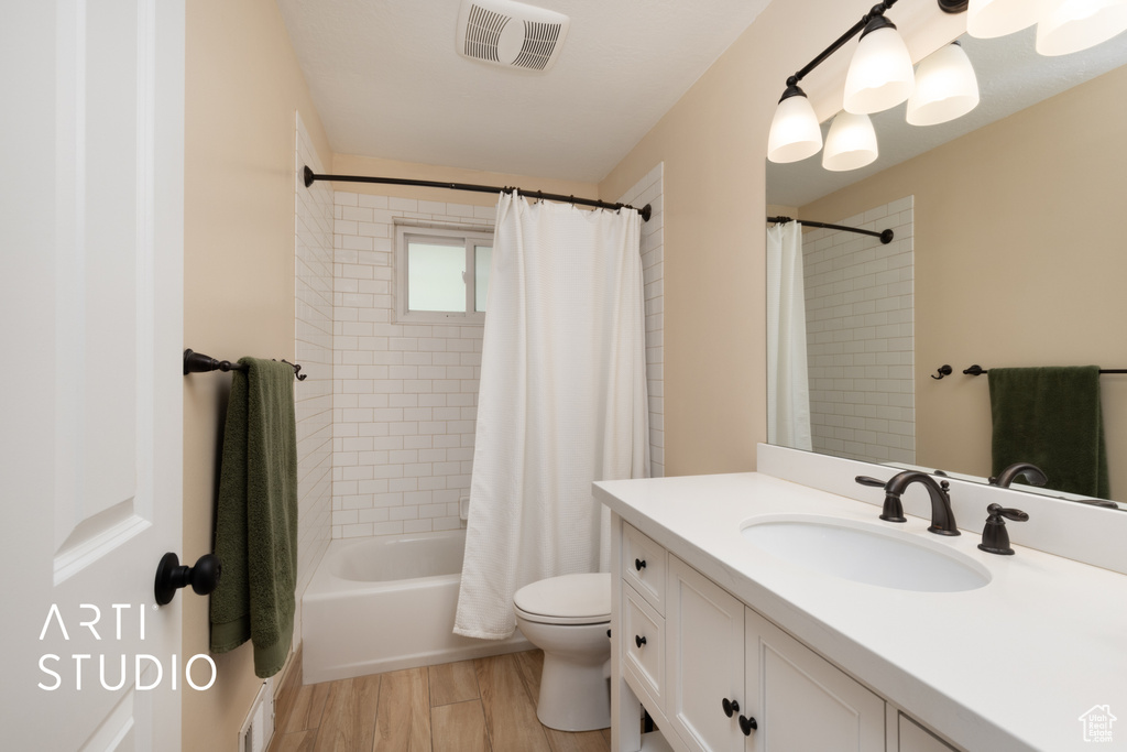 Bathroom with toilet, vanity, shower / bath combo, and wood finished floors