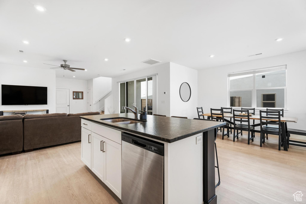 Kitchen featuring dishwasher, a sink, dark countertops, recessed lighting, and a kitchen island with sink
