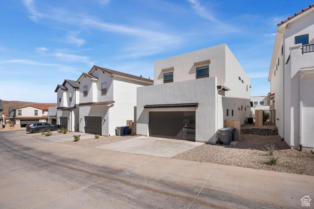 View of property exterior with a garage, a residential view, stucco siding, and driveway