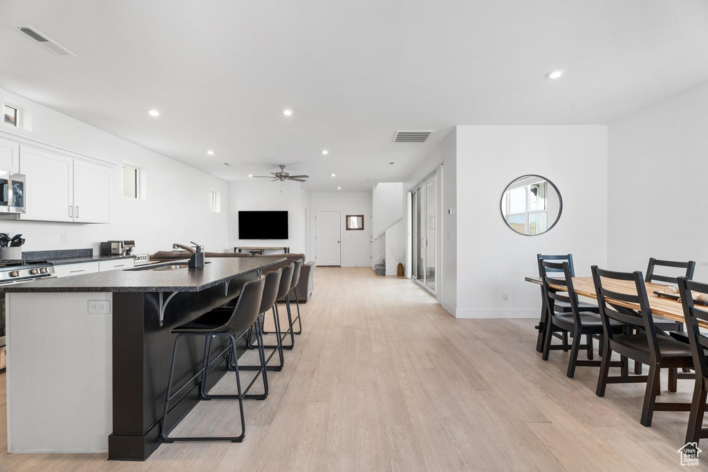 Kitchen with a sink, appliances with stainless steel finishes, dark countertops, an island with sink, and ceiling fan