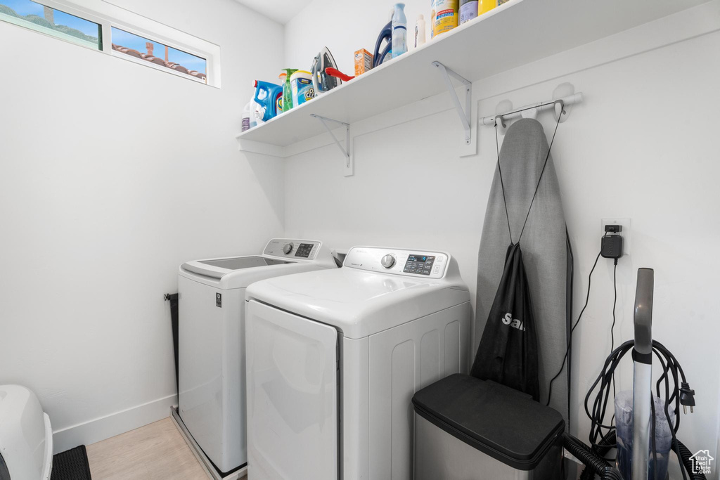 Washroom featuring independent washer and dryer, baseboards, and light wood-style floors