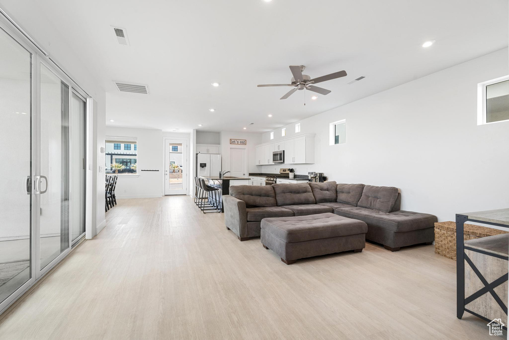 Living room featuring light wood-type flooring, ceiling fan, and recessed lighting