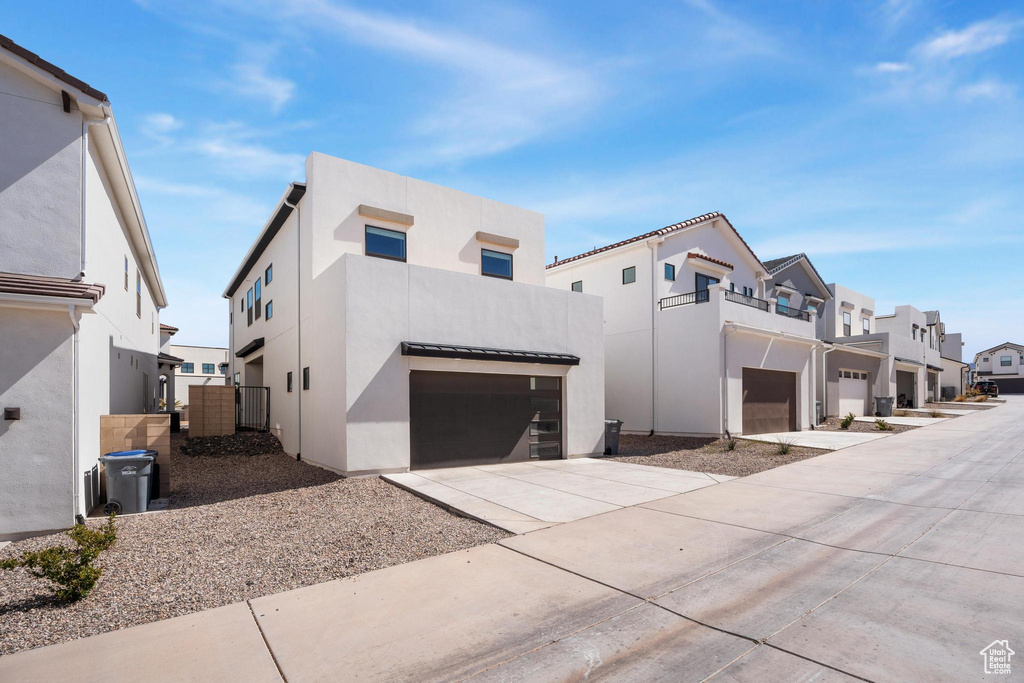 View of front facade featuring stucco siding, concrete driveway, and an attached garage