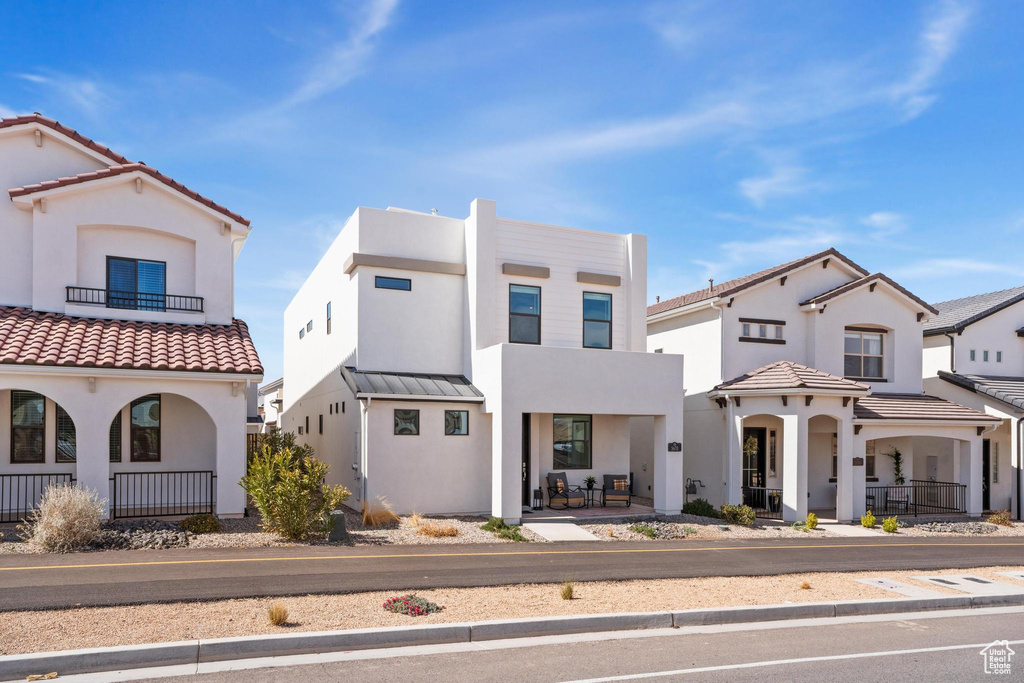 View of front facade featuring covered porch, stucco siding, a balcony, and a tiled roof