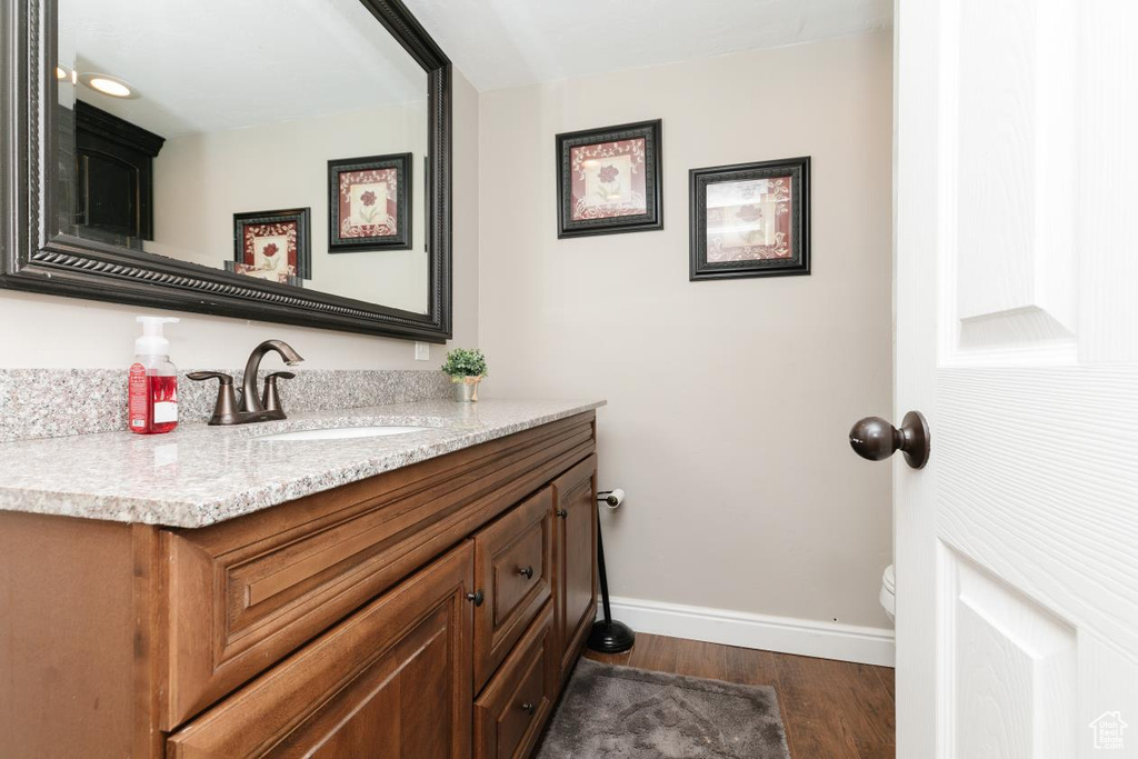 Bathroom featuring baseboards, wood finished floors, vanity, and toilet
