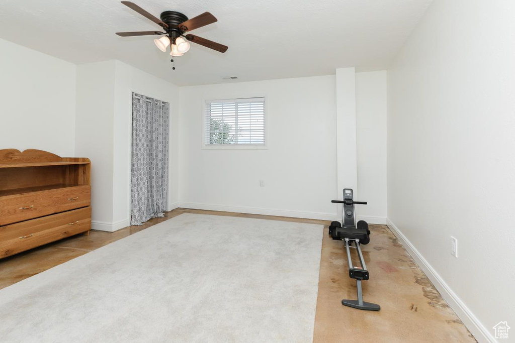 Exercise area featuring a ceiling fan, carpet floors, and baseboards