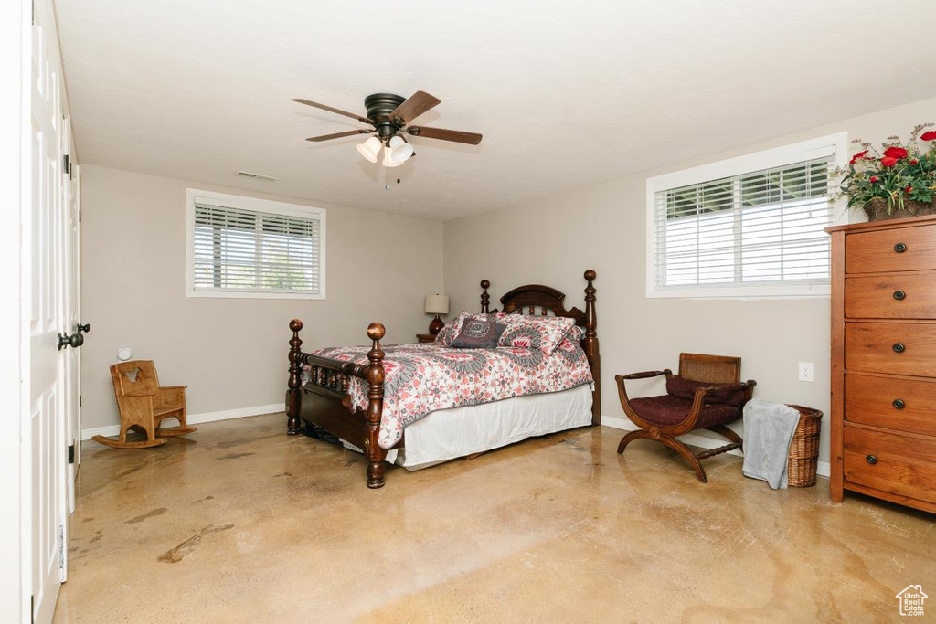 Bedroom featuring finished concrete floors, baseboards, and ceiling fan