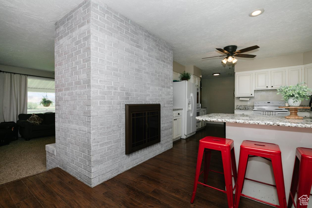 Kitchen with white appliances, dark wood-type flooring, a textured ceiling, a ceiling fan, and white cabinetry