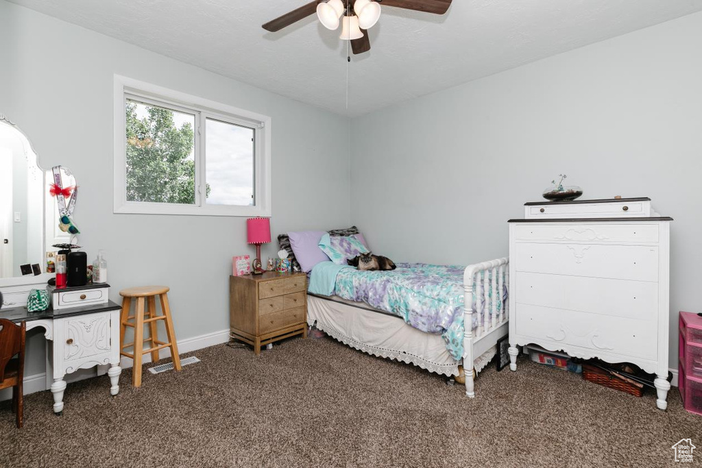Carpeted bedroom featuring ceiling fan and baseboards