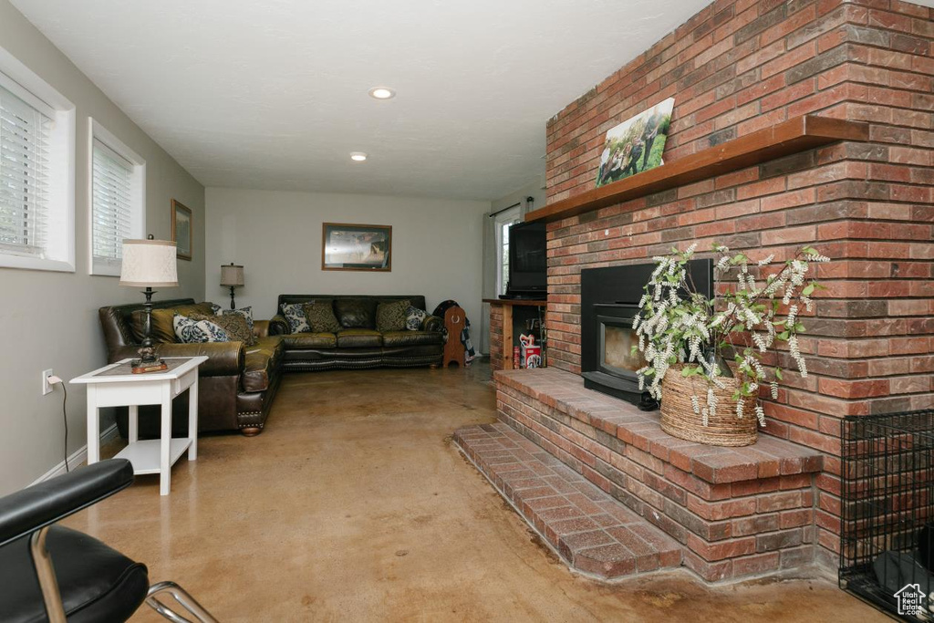 Living room with finished concrete flooring, a brick fireplace, and recessed lighting