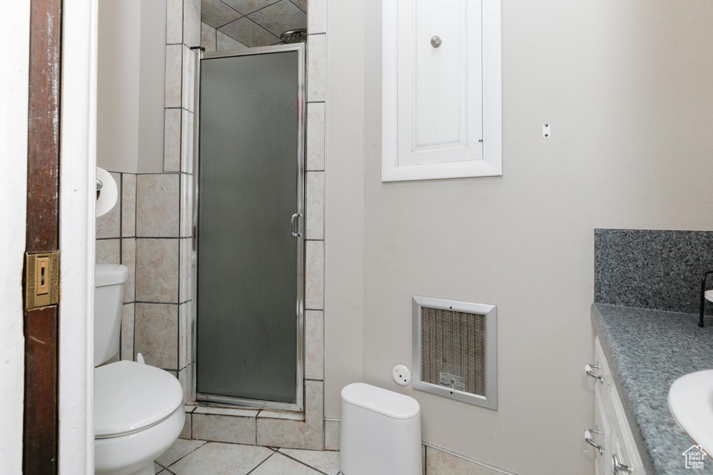 Bathroom featuring toilet, vanity, a shower stall, and tile patterned flooring
