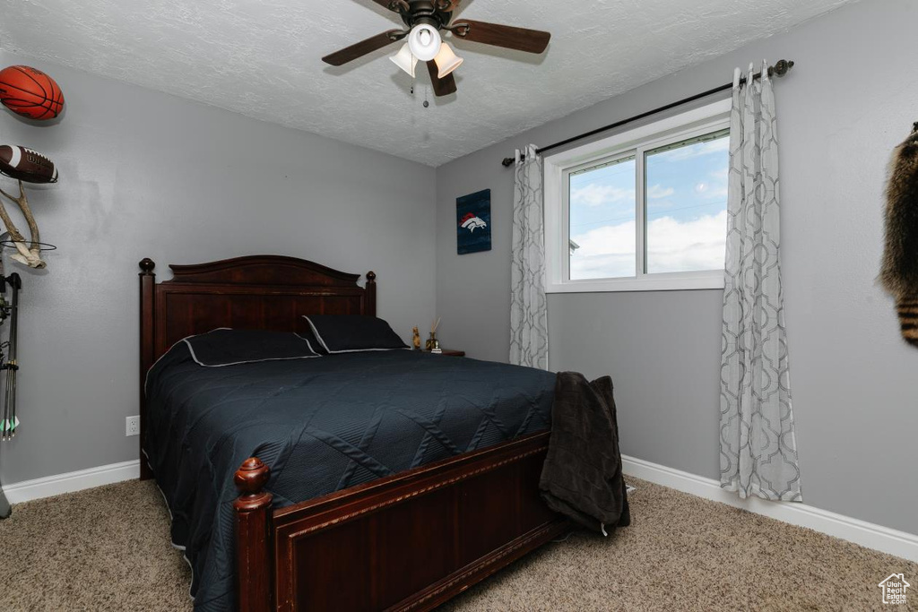 Bedroom featuring baseboards, light colored carpet, a textured ceiling, and a ceiling fan