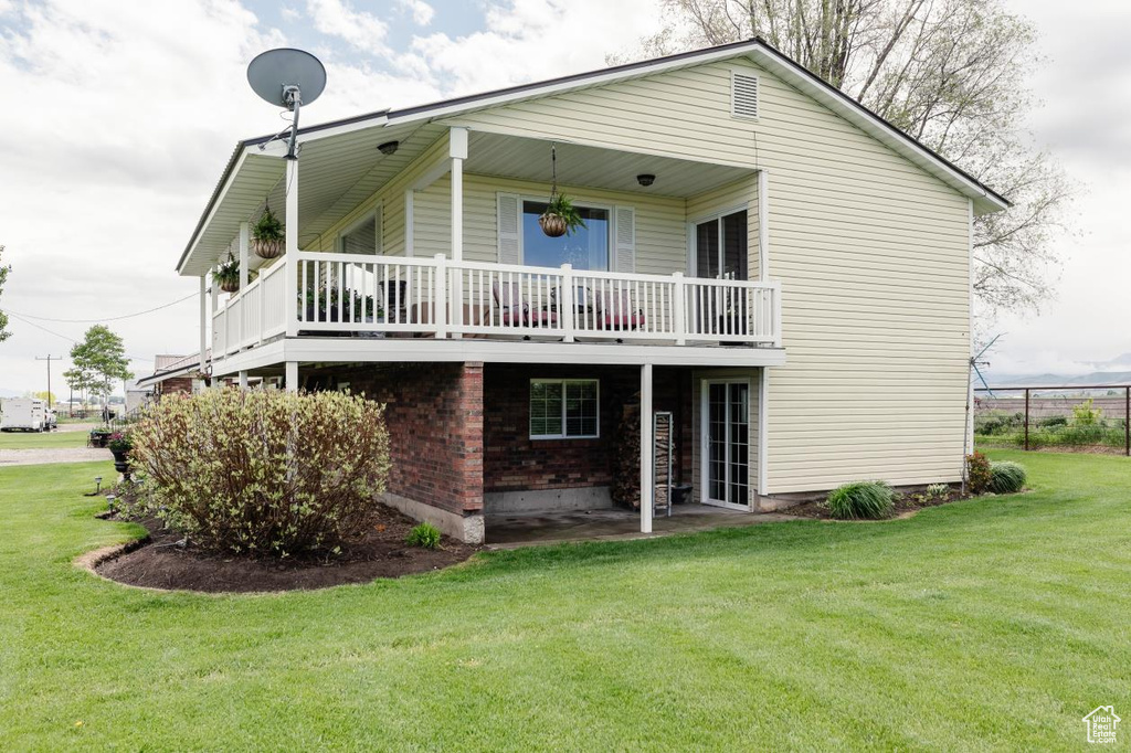 Back of house with a yard and brick siding