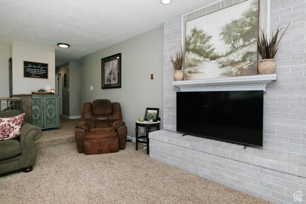 Carpeted living room featuring a fireplace, baseboards, and a textured ceiling