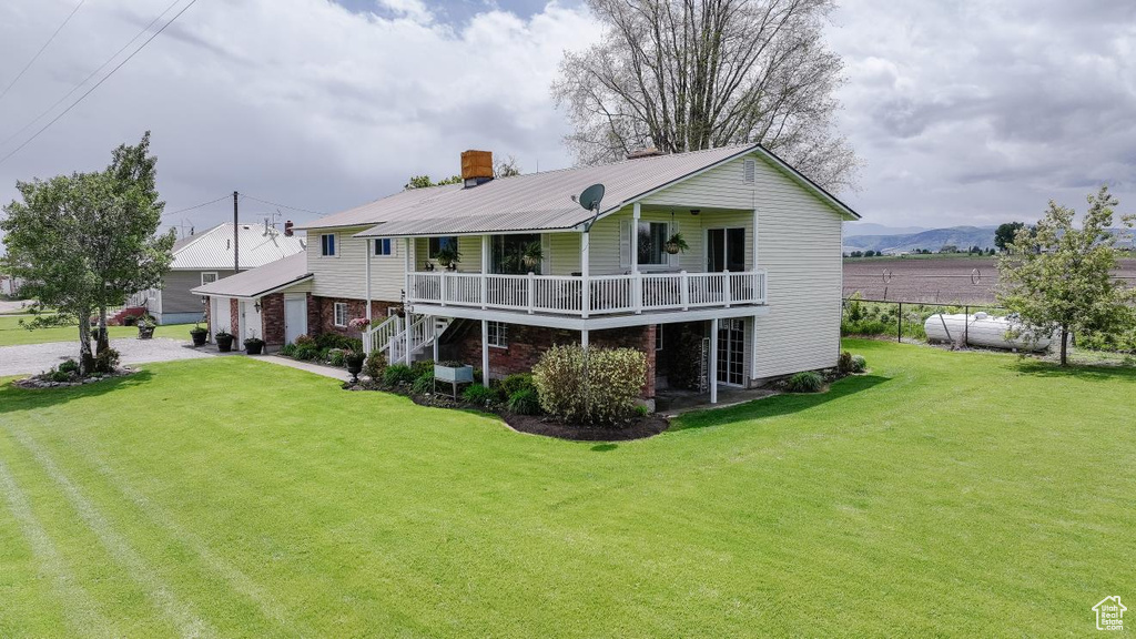 Rear view of property featuring a lawn, metal roof, and a detached garage