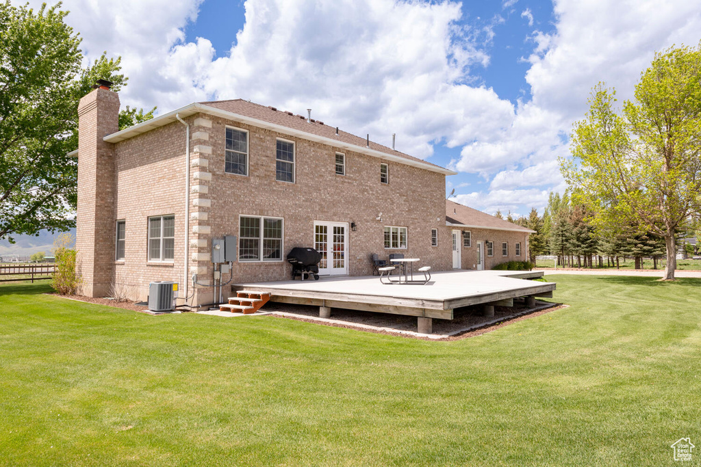 Back of property featuring a chimney, a wooden deck, brick siding, cooling unit, and french doors