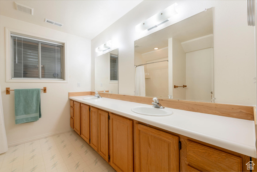 Full bath with baseboards, double vanity, and curtained shower