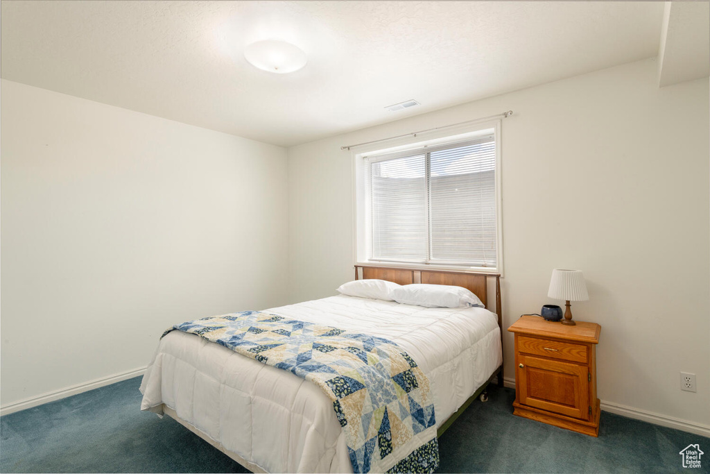 Bedroom with dark colored carpet and baseboards