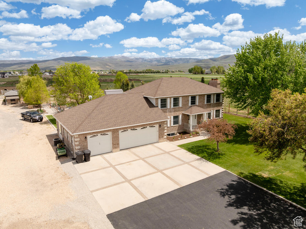 View of front of property with an attached garage, concrete driveway, a mountain view, and brick siding