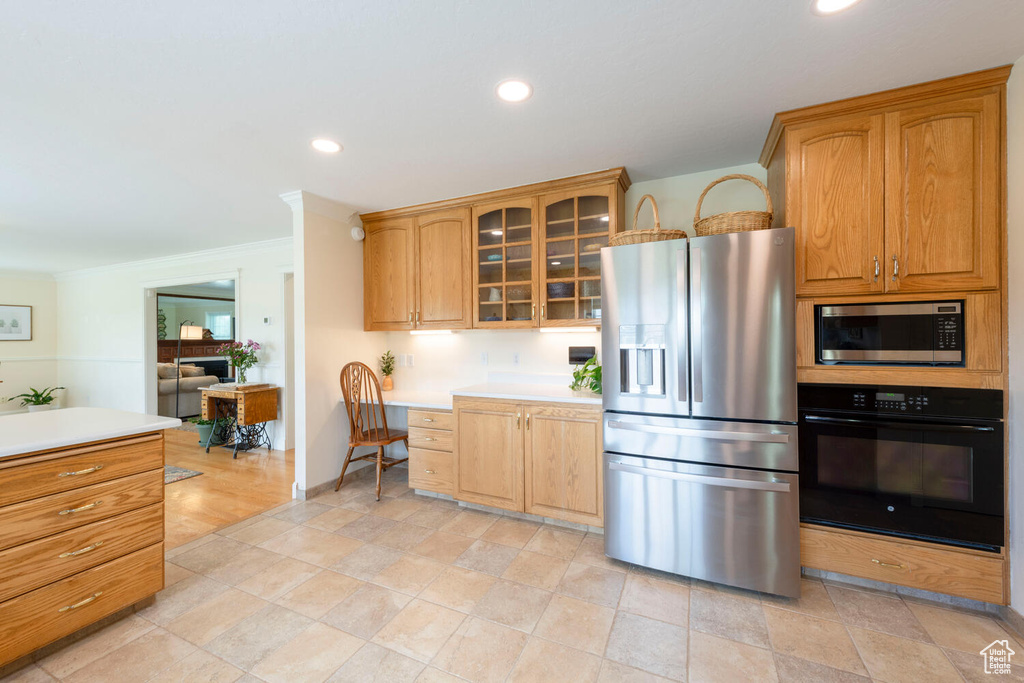 Kitchen featuring stainless steel appliances, light countertops, glass insert cabinets, recessed lighting, and ornamental molding