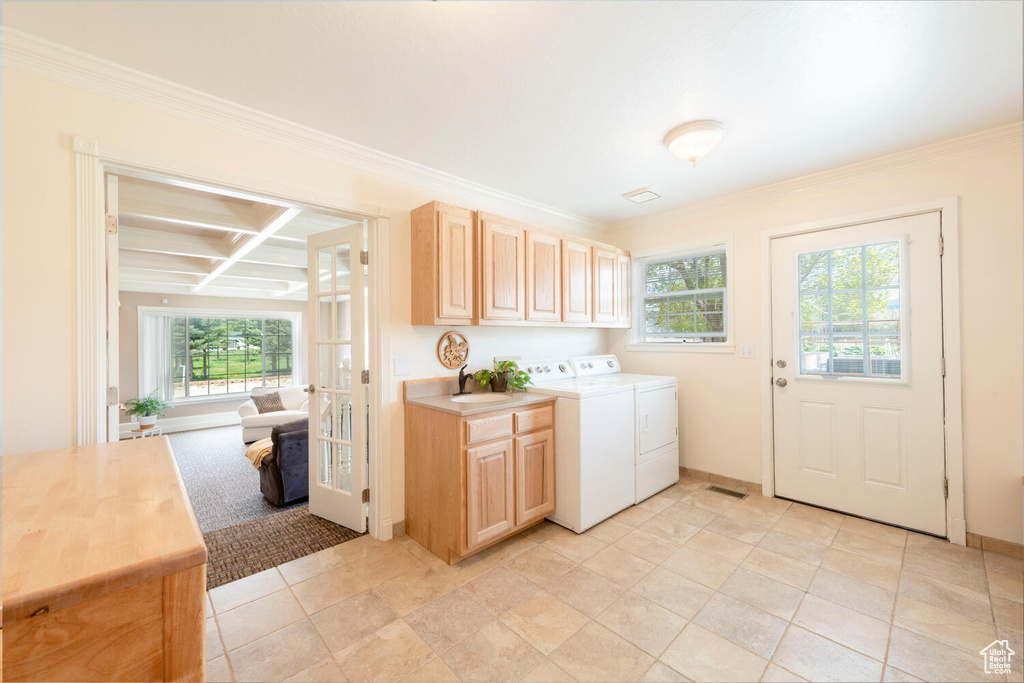 Washroom with cabinet space, separate washer and dryer, ornamental molding, and baseboards
