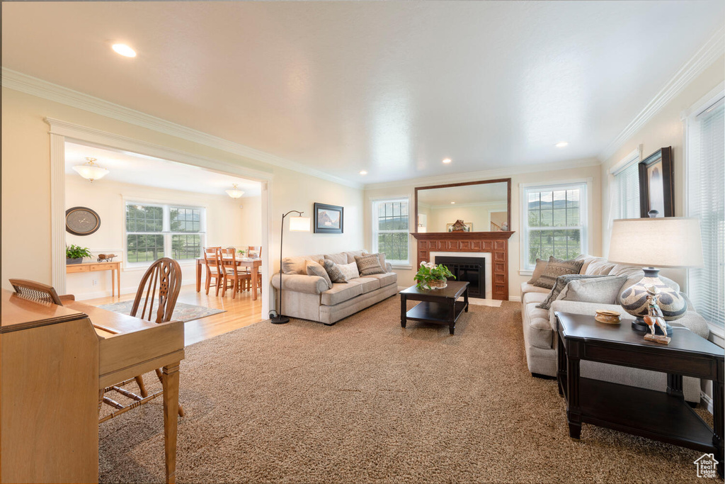 Living room with plenty of natural light, ornamental molding, a fireplace with flush hearth, and recessed lighting