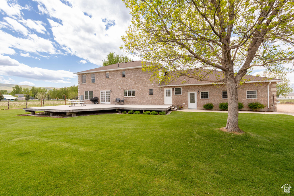 Back of property featuring a deck with mountain view, a yard, and brick siding