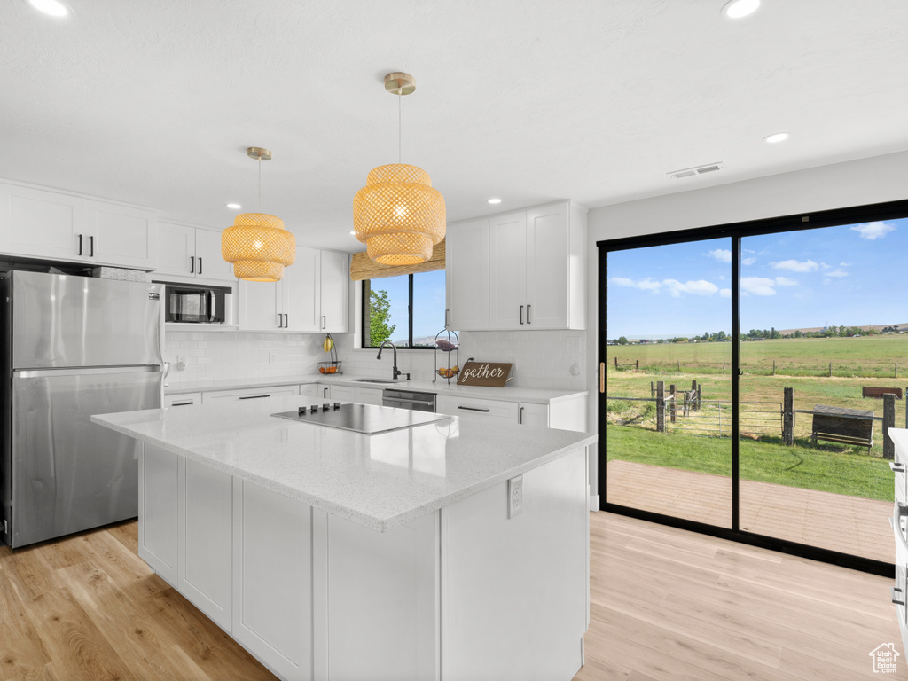 Kitchen with appliances with stainless steel finishes, decorative backsplash, a kitchen island, light wood-style floors, and recessed lighting