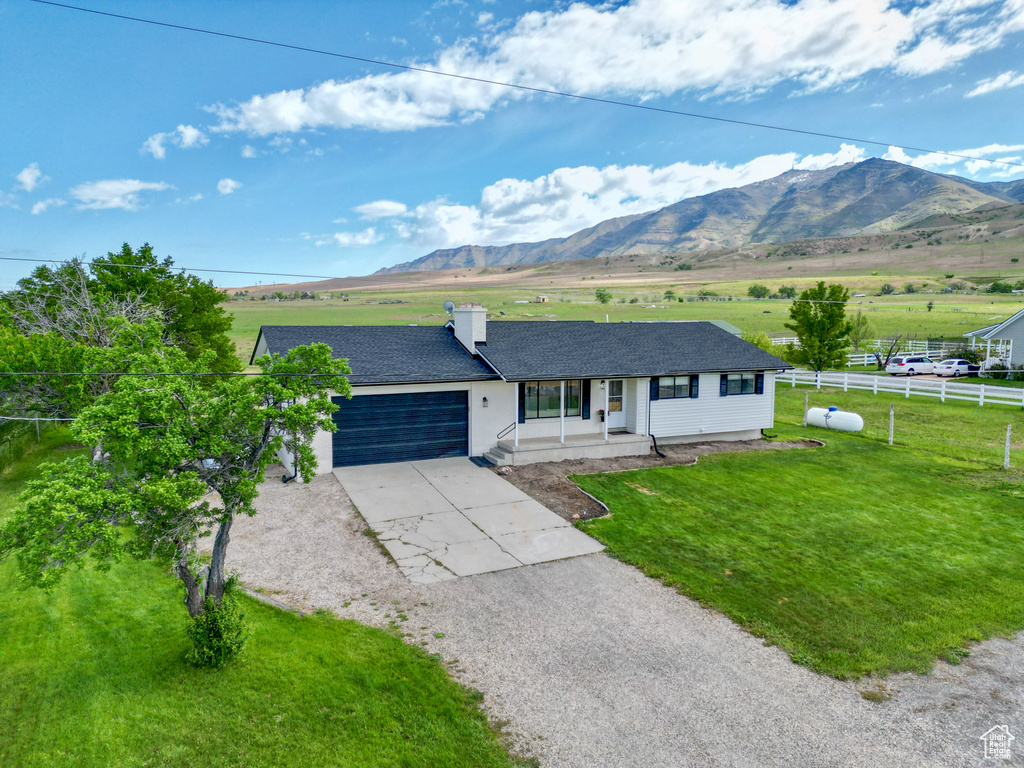 Ranch-style house featuring concrete driveway, a garage, a porch, and a mountain view