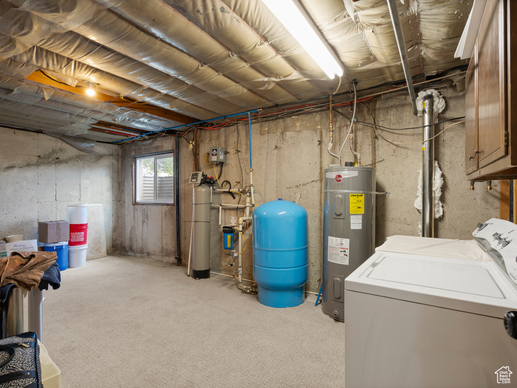 Basement featuring electric water heater, a water pressure tank, and washing machine and dryer