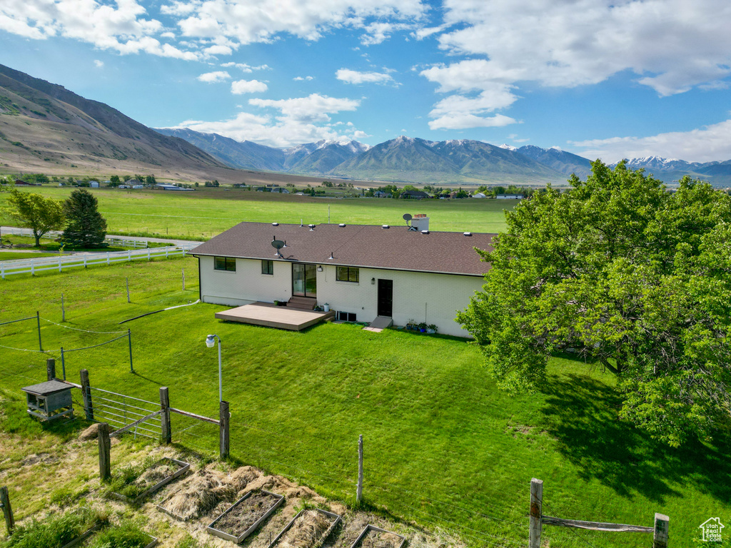 Back of house featuring a deck with mountain view, stucco siding, and a rural view