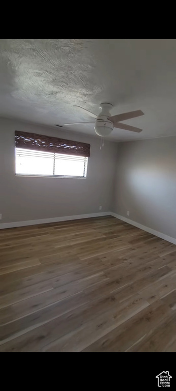 Spare room featuring baseboards, wood finished floors, and a ceiling fan