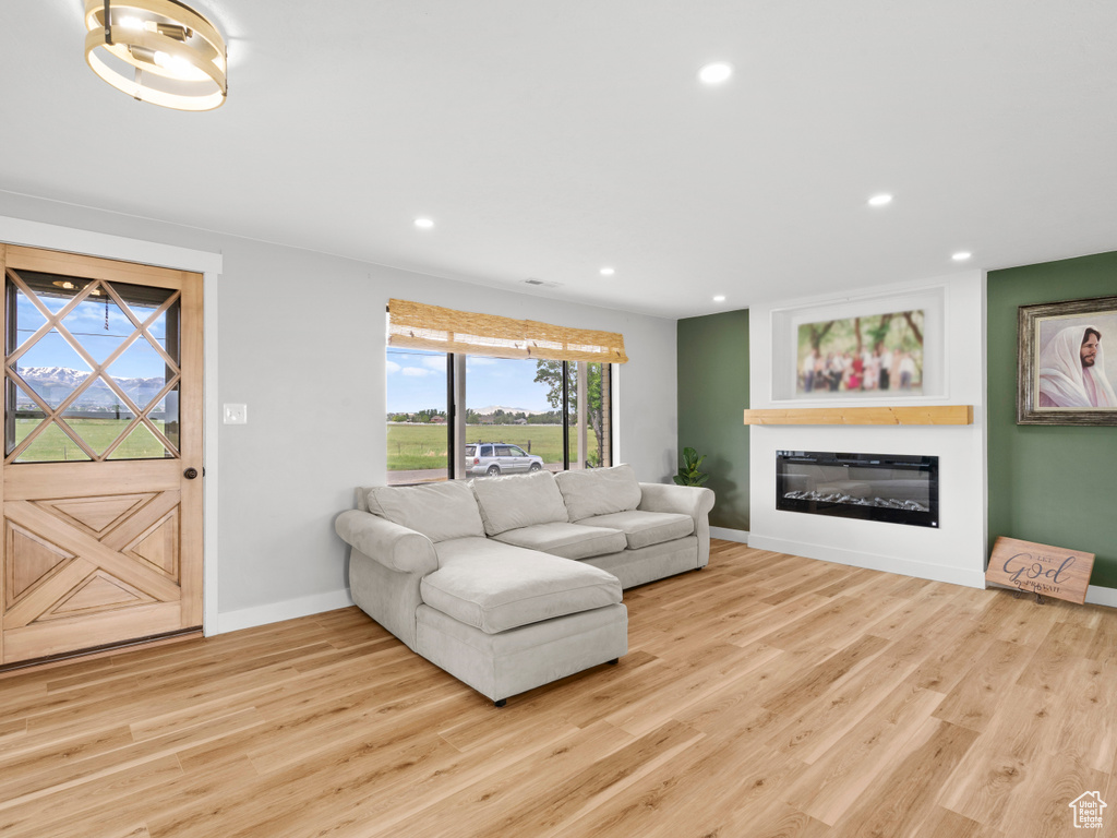 Living area featuring baseboards, wood finished floors, recessed lighting, and a glass covered fireplace