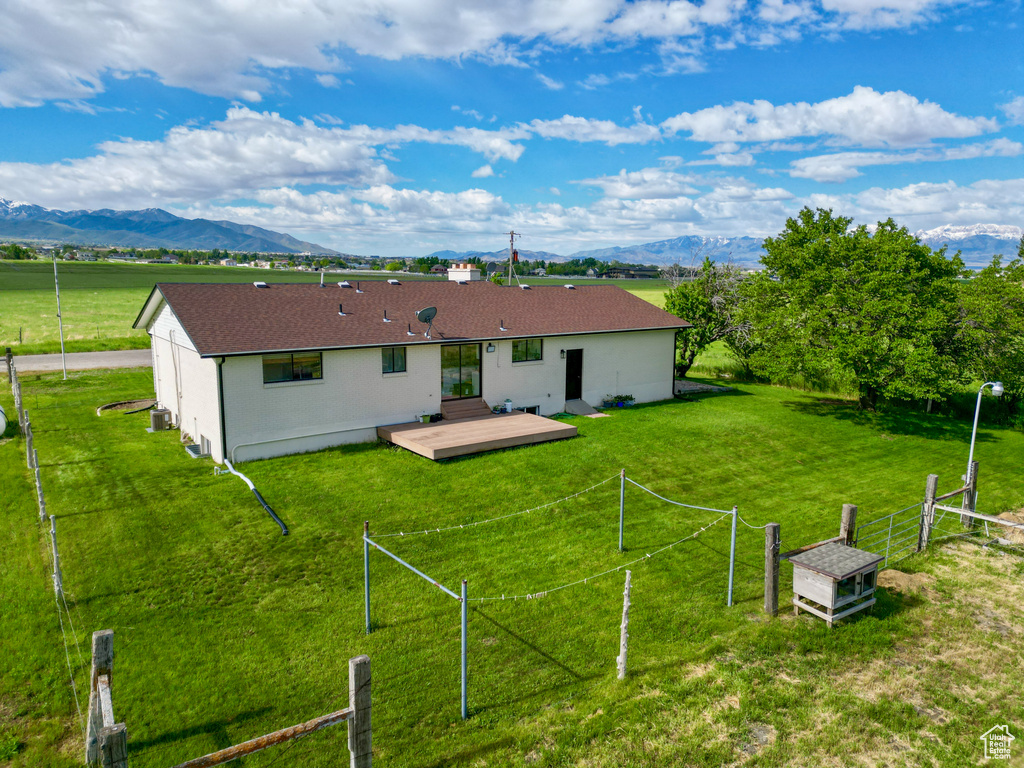 Back of house with a deck with mountain view and a shingled roof