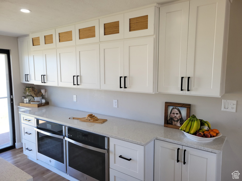 Kitchen featuring white cabinetry, glass insert cabinets, light wood-style floors, and recessed lighting