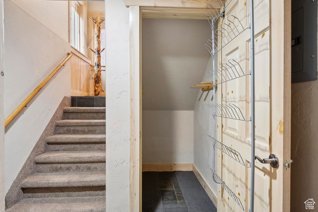 Stairs featuring electric panel and baseboards