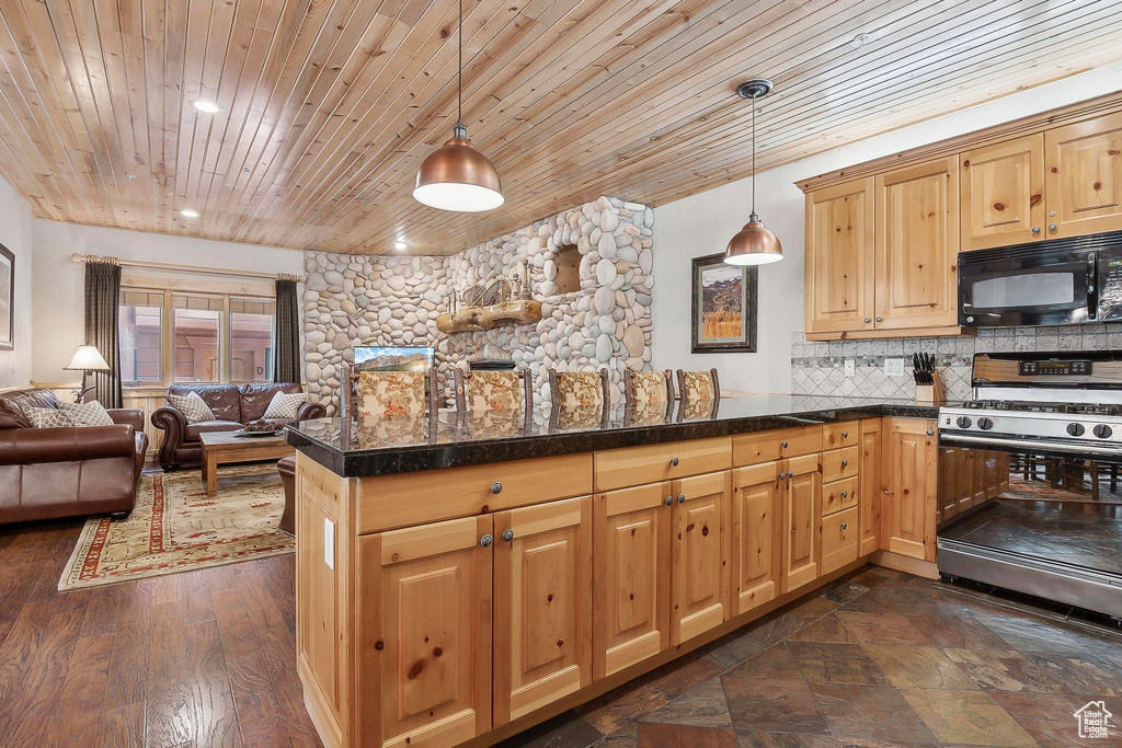Kitchen with range with gas stovetop, black microwave, wood ceiling, open floor plan, and a peninsula