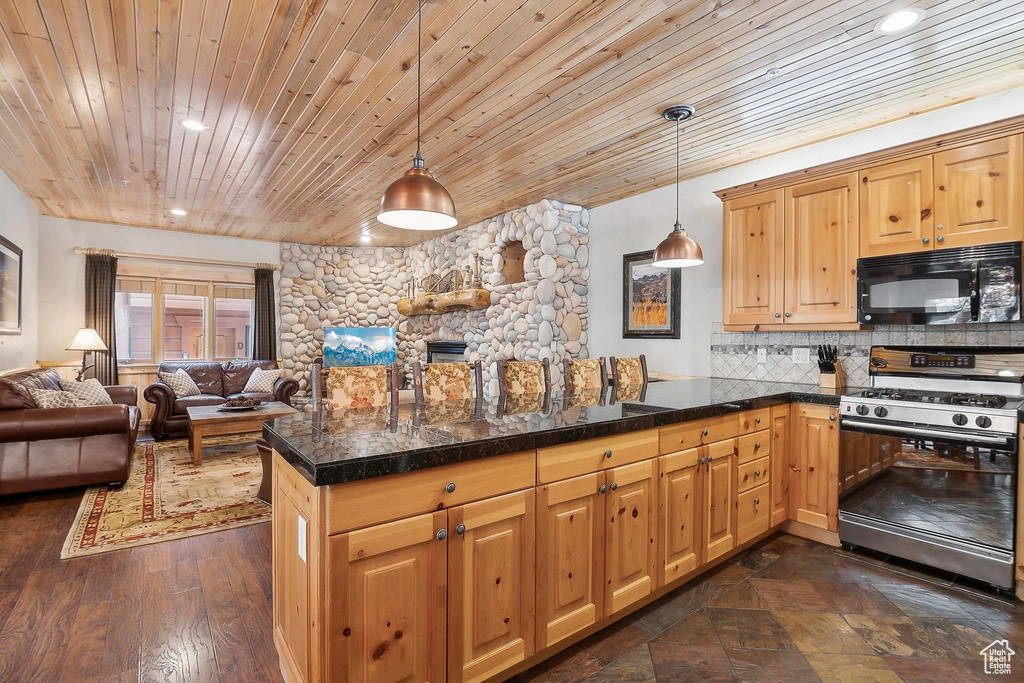 Kitchen featuring black microwave, gas range, a peninsula, wood ceiling, and open floor plan