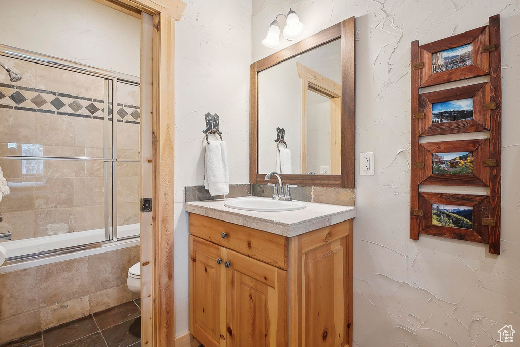 Bathroom featuring tiled shower / bath, toilet, and vanity