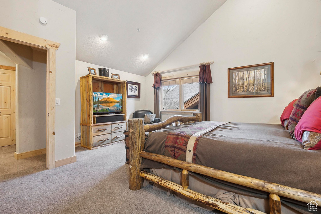 Carpeted bedroom featuring baseboards and high vaulted ceiling